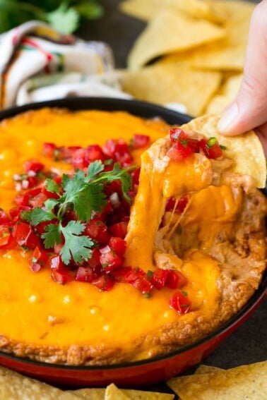 A tortilla chip scooping out a serving of Mexican bean dip.