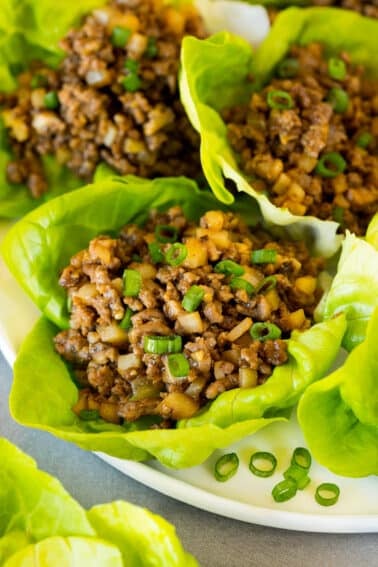 A plate full of beef lettuce wraps garnished with green onions.