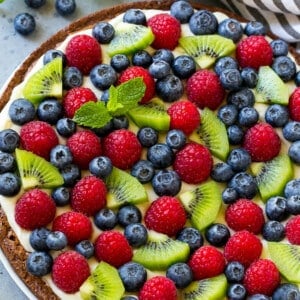 Brownie pizza topped with cream cheese frosting and fresh fruit.