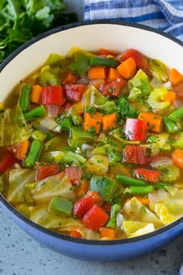 A pot of cabbage soup with carrots, celery, bell peppers and green beans.