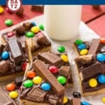 Several candy bar blondies served on parchment paper next to a glass of milk.