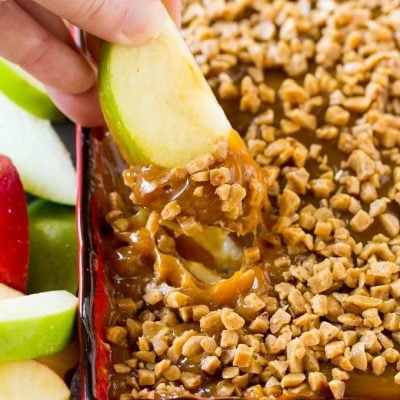 A hand scooping out a serving of caramel apple dip.