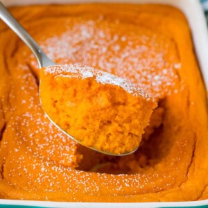 A spoon serving up a portion of carrot souffle.