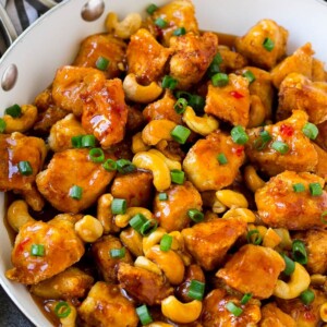 A pan of cashew chicken topped with sliced green onions.