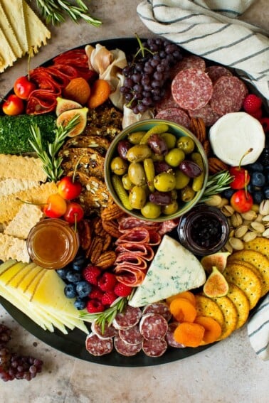 A charcuterie board filled with meats, cheeses, crackers, fruit and nuts.