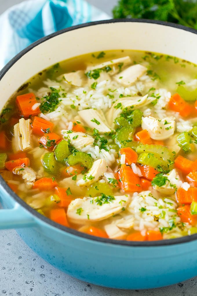 Chicken and rice soup in a blue pot, garnished with parsley.