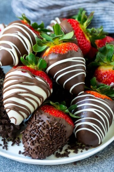 A plate of chocolate covered strawberries dipped in white and dark chocolate.