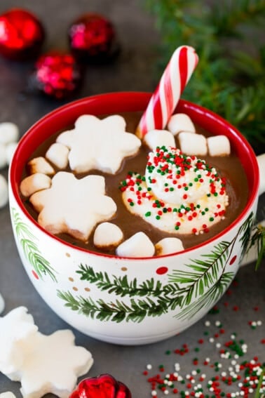 A mug of Christmas hot chocolate topped with sprinkles, whipped cream and marshmallows.