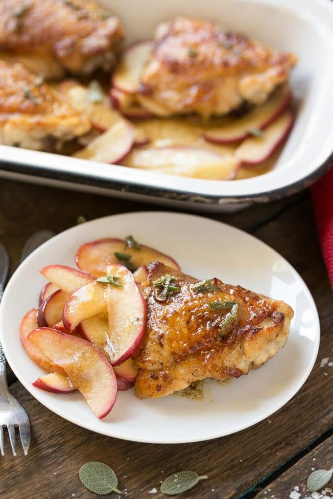 Apple cider glazed chicken thighs on a plate served cooked apples.