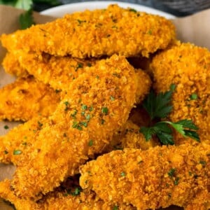 Cornflake chicken on a serving plate, garnished with fresh parsley.