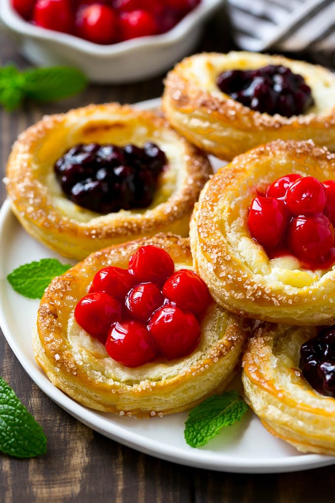 A platter of cream cheese danish topped with fruit.