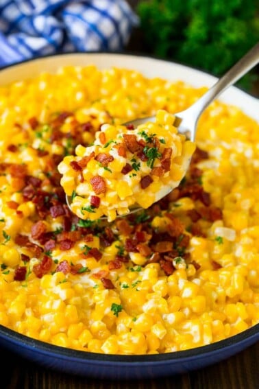 A spoonful of creamed corn topped with bacon and fresh herbs.