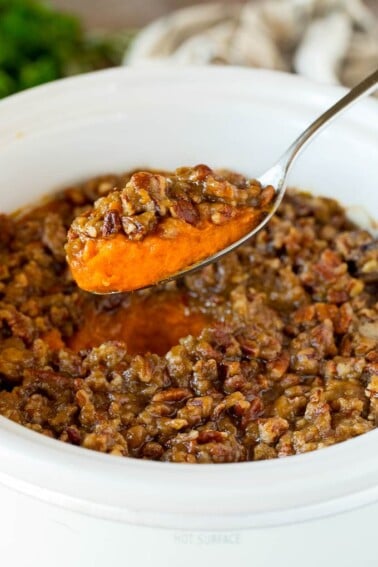 A spoon serving up a portion of crock pot sweet potato casserole.