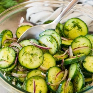 A bowl of cucumber dill salad with a spoon in it.