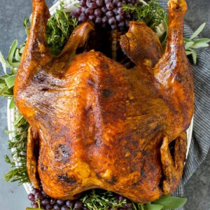 A whole deep fried turkey on a serving platter with herbs.