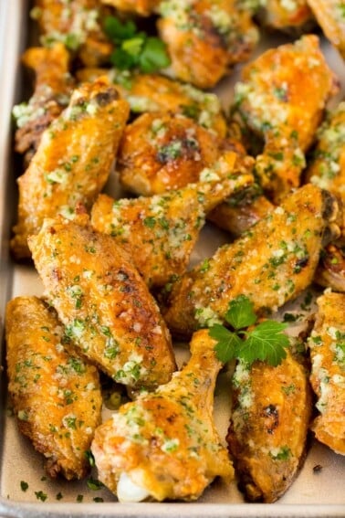 A pan of garlic parmesan wings garnished with parsley.