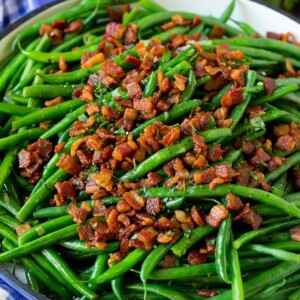 Green beans with bacon in a skillet, topped with parsley.