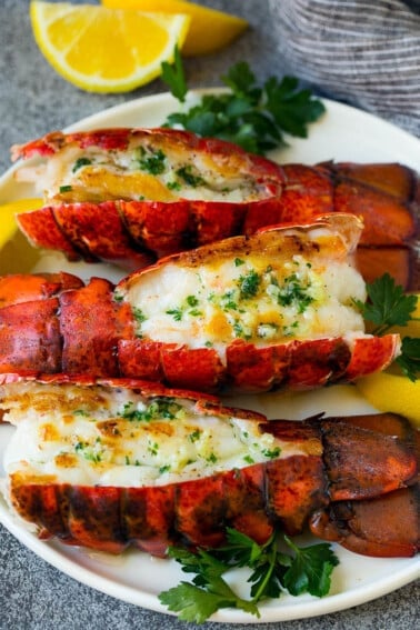 Grilled lobster tail topped with garlic butter and garnished with lemon and parsley.