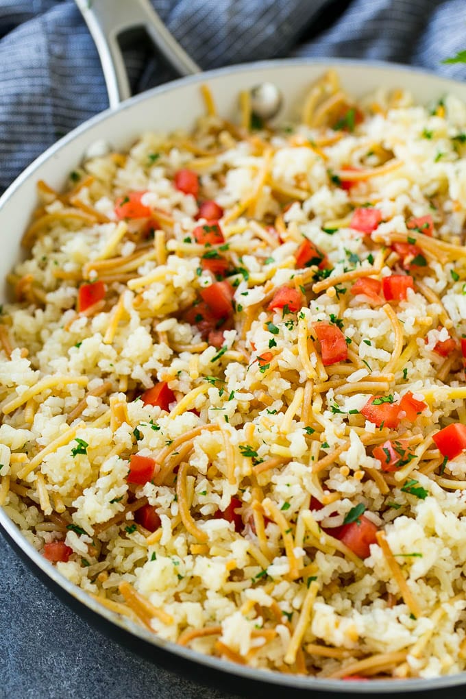 Homemade rice a roni topped with tomatoes and herbs, all in a skillet.