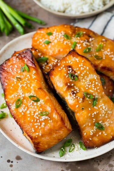 A platter of miso salmon fillets topped with sesame seeds and green onions.