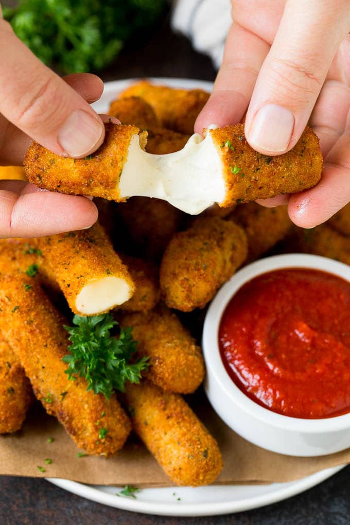 A hand pulling apart mozzarella sticks.