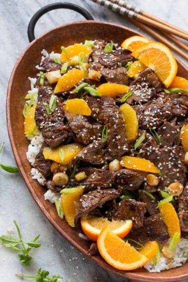 Orange beef in a pan served over rice.