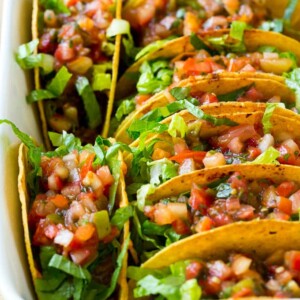 These oven baked beef tacos are filled with beans, meat and melted cheese, then topped off with shredded lettuce and fresh salsa. The best way to make tacos for a crowd!