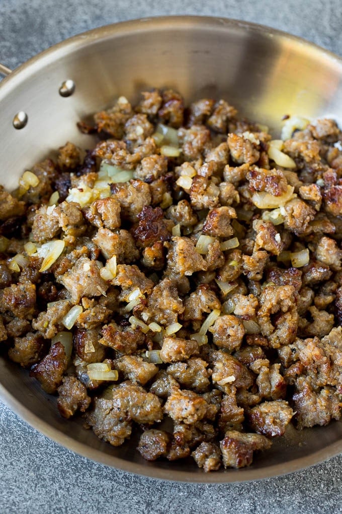 Browned sausage and onions in a pan.