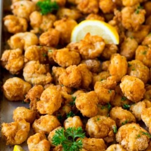 Popcorn shrimp on a sheet pan, garnished with lemon and parsley.