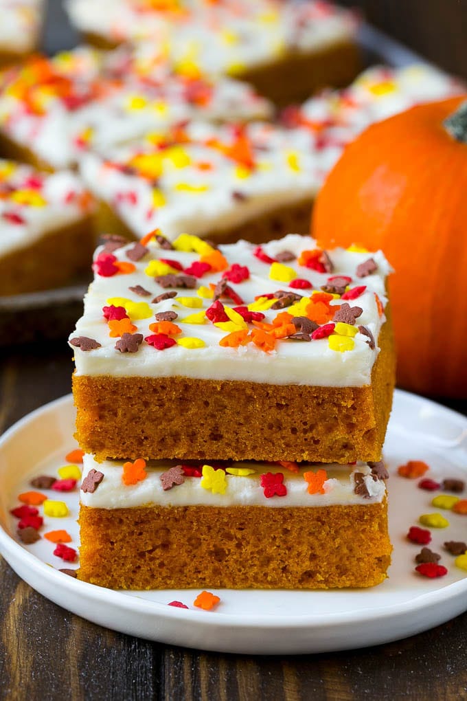 A stack of pumpkin bars topped with frosting and sprinkles.