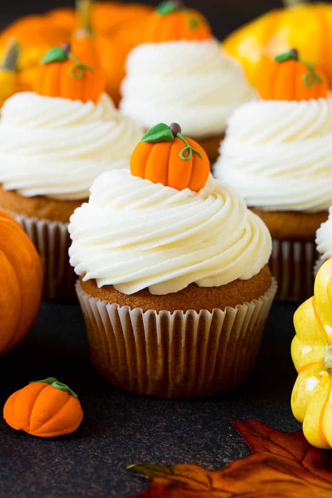 Pumpkin cupcakes topped with cream cheese frosting and candy pumpkins.