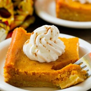 A piece of pumpkin gooey butter cake with a fork in it.