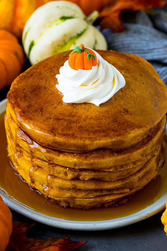 Pumpkin pancakes topped with maple syrup and whipped cream.