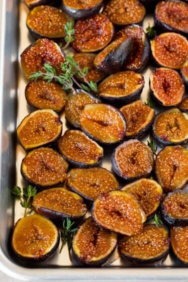 Roasted figs on a sheet pan, garnished with sprigs of thyme.