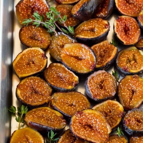 Roasted figs on a sheet pan, garnished with sprigs of thyme.