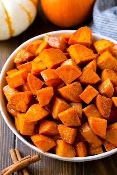 A bowl of maple roasted sweet potatoes with cinnamon and butter.