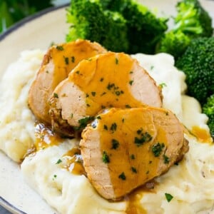 Sliced slow cooker pork tenderloin served over mashed potatoes with broccoli.