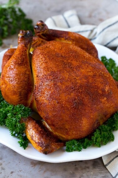 Smoked chicken on a serving platter garnished with parsley.