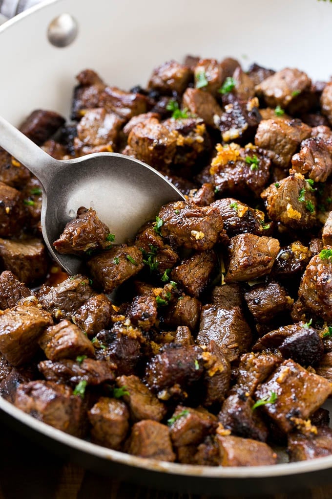 A pan of steak bites with a serving spoon.