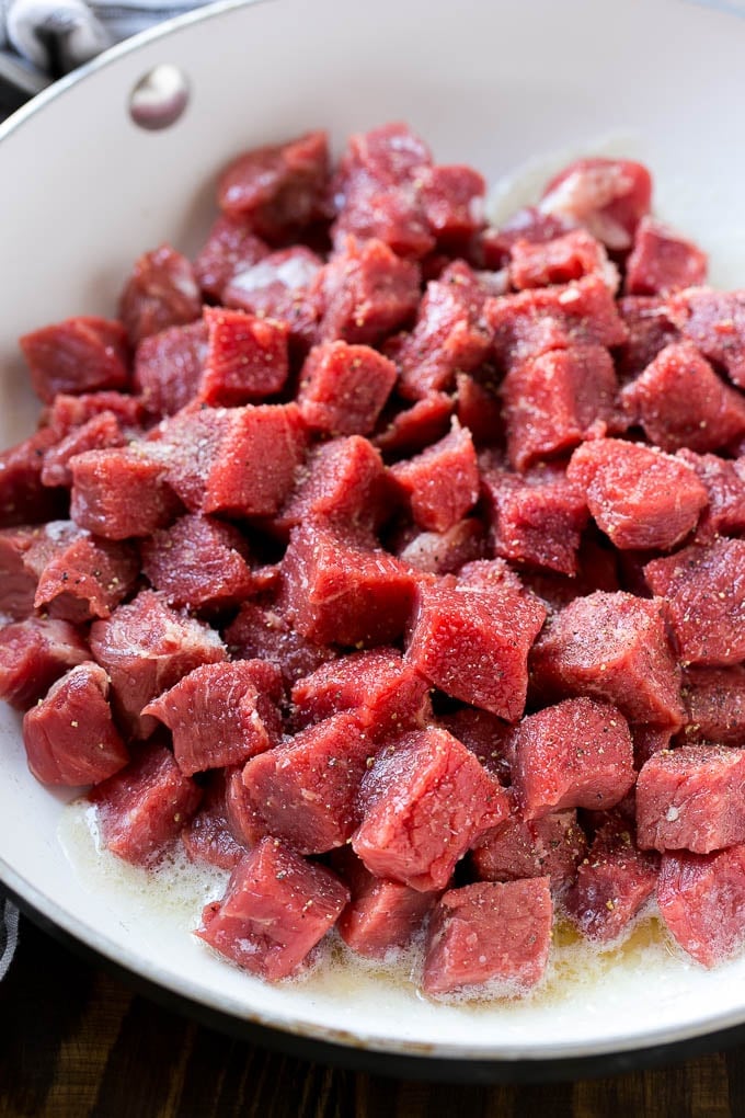 Cubes of raw beef seasoned with salt and black pepper.