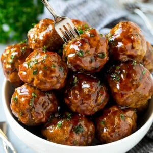 A bowl of sweet and sour meatballs with a cocktail fork in it.