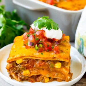 A slice of taco lasagna topped with salsa, sour cream and cilantro.