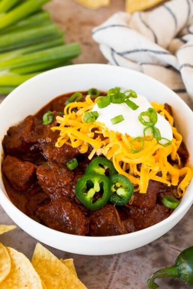 A bowl of Texas chili topped with cheese and sour cream.