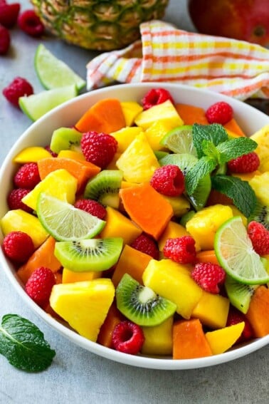 A bowl of tropical fruit salad with mango, raspberries, papaya, kiwi and pineapple tossed in honey lime dressing.