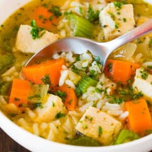 A bowl of turkey and rice soup with a spoon in it.