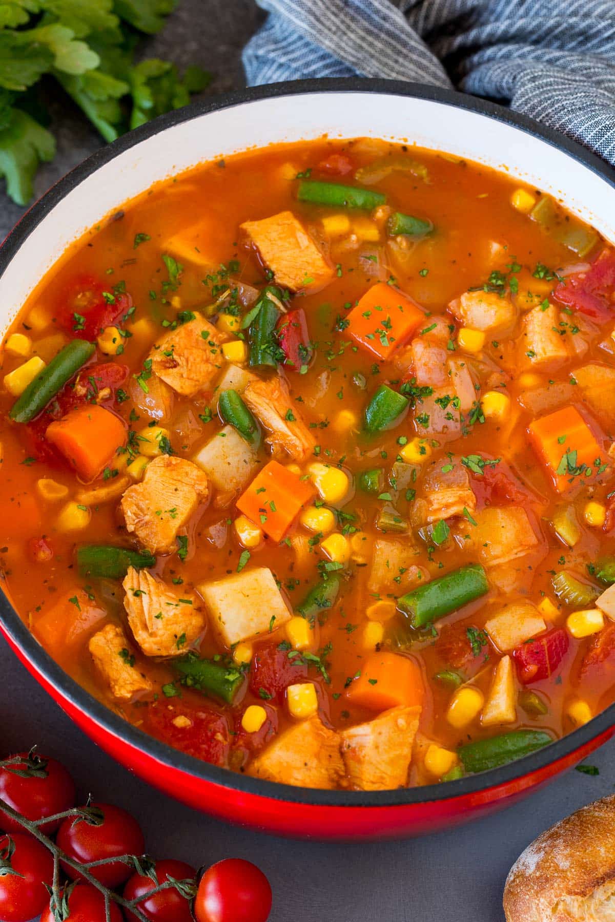 A pot of turkey vegetable soup with a garnish of fresh parsley on top.