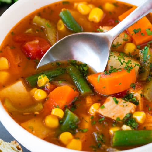 A bowl of turkey vegetable soup with a spoon in it.