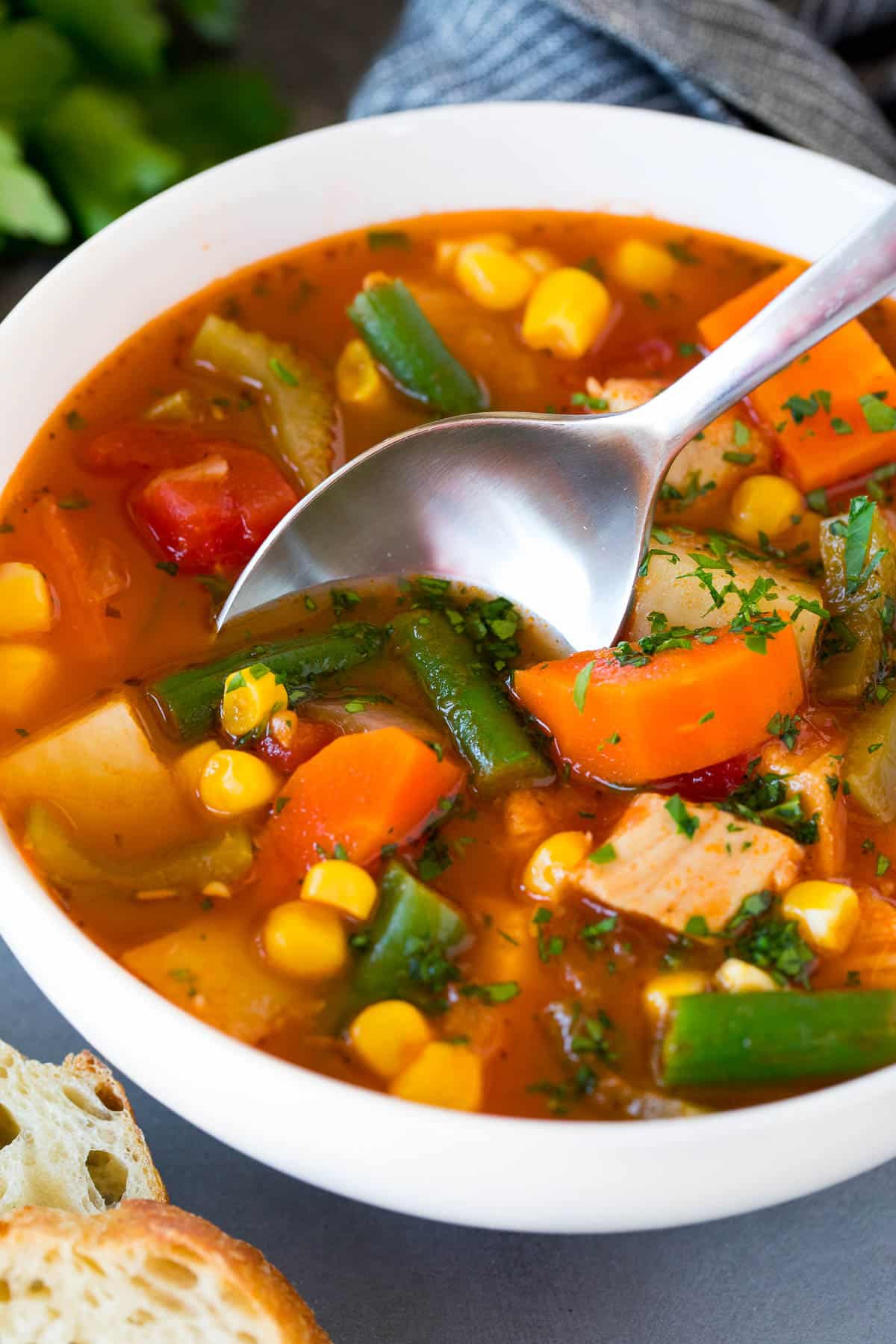 A bowl of turkey vegetable soup with a spoon in it.